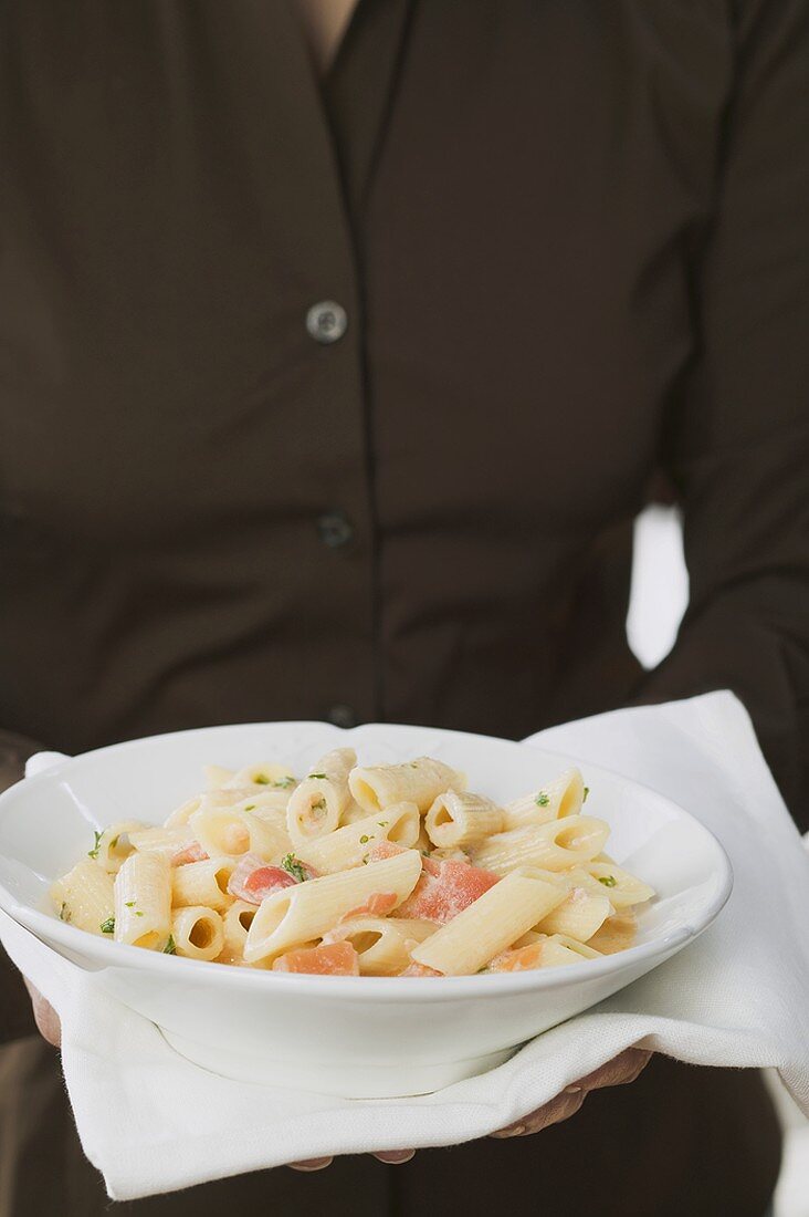 Frau hält Teller Penne mit Tomaten