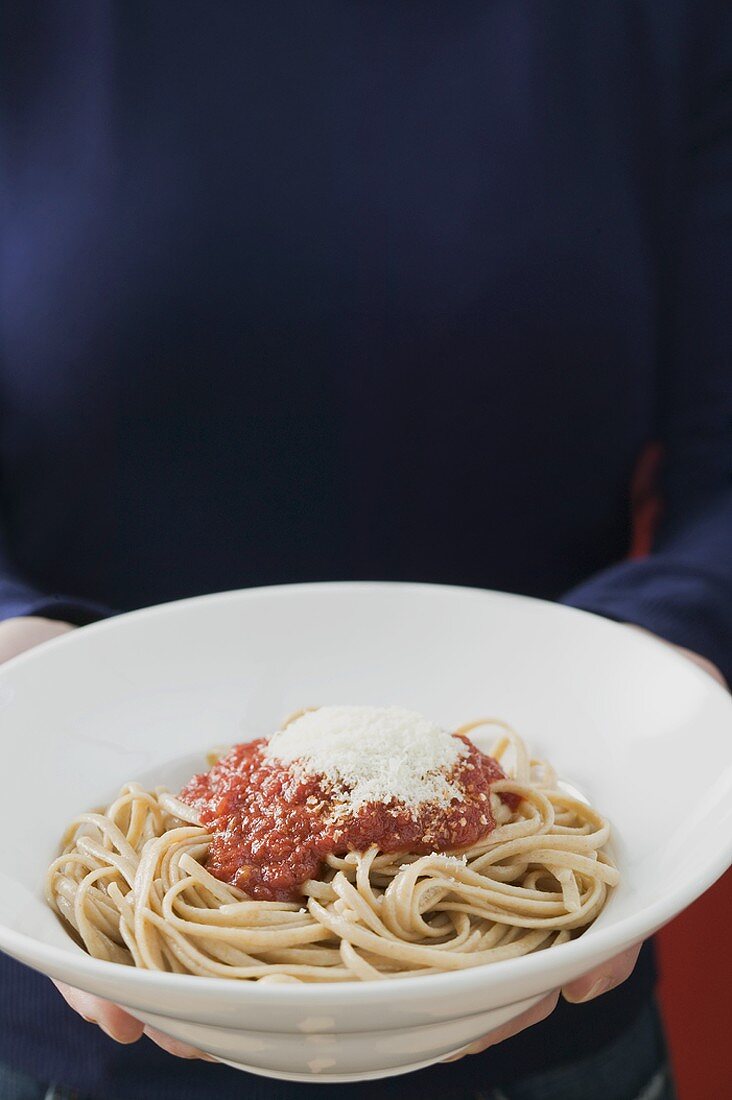 Hände halten Teller Linguine mit Tomatensauce