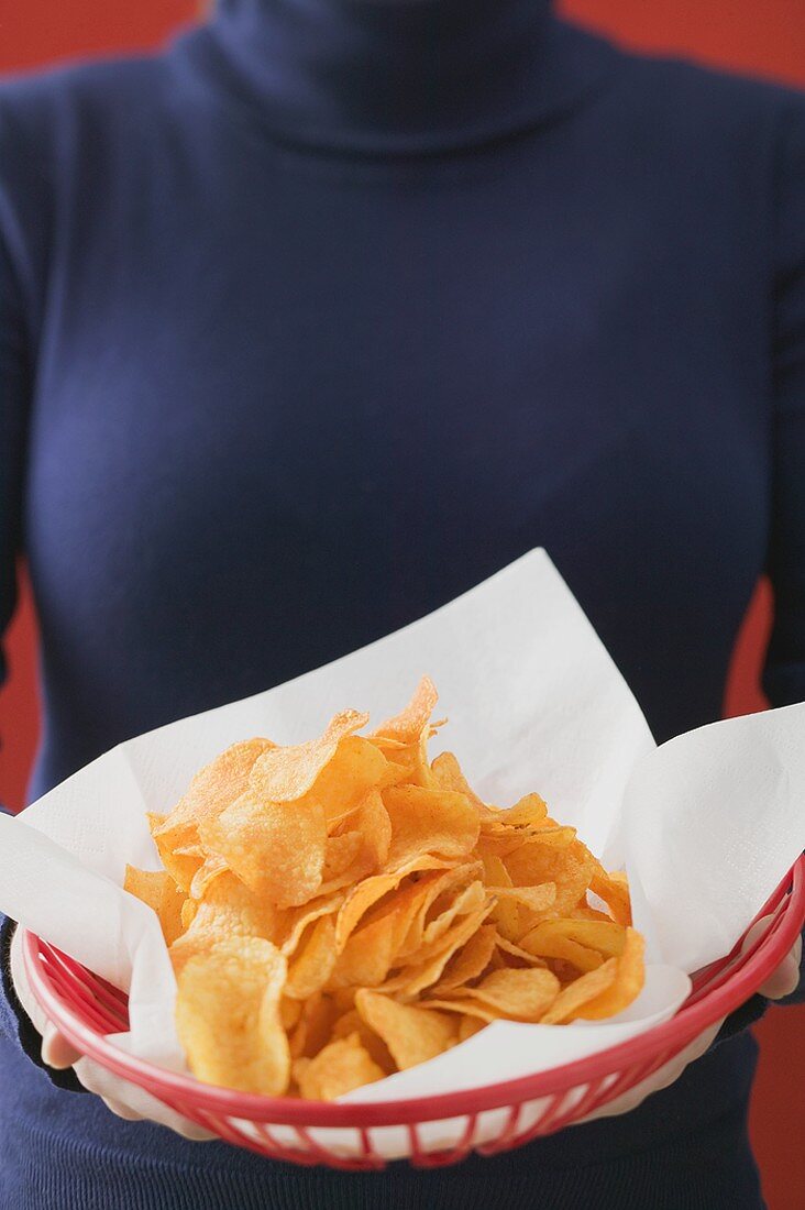 Frau hält Korb mit Chips