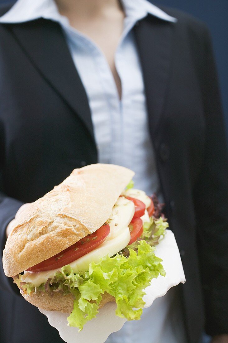 Frau hält Ciabatta mit Mozzarella und Tomaten