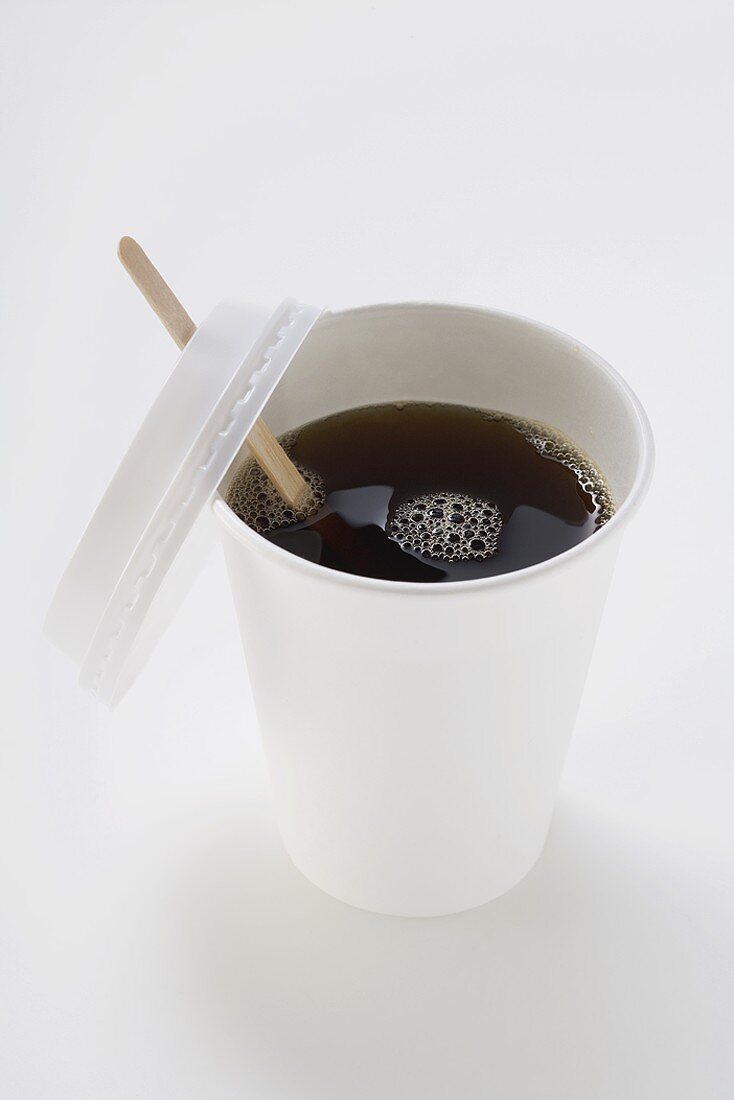 Black coffee in paper cup with wooden stirrer