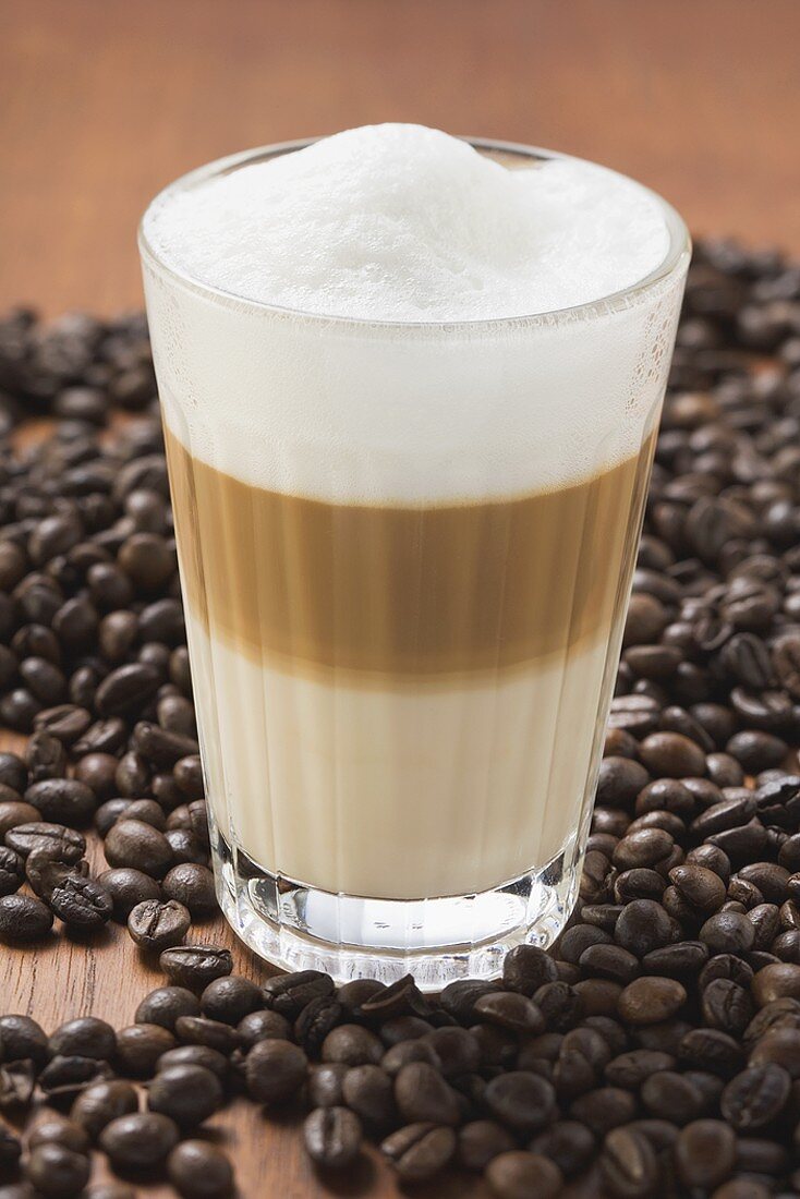 Latte Macchiato im Glas auf Kaffeebohnen