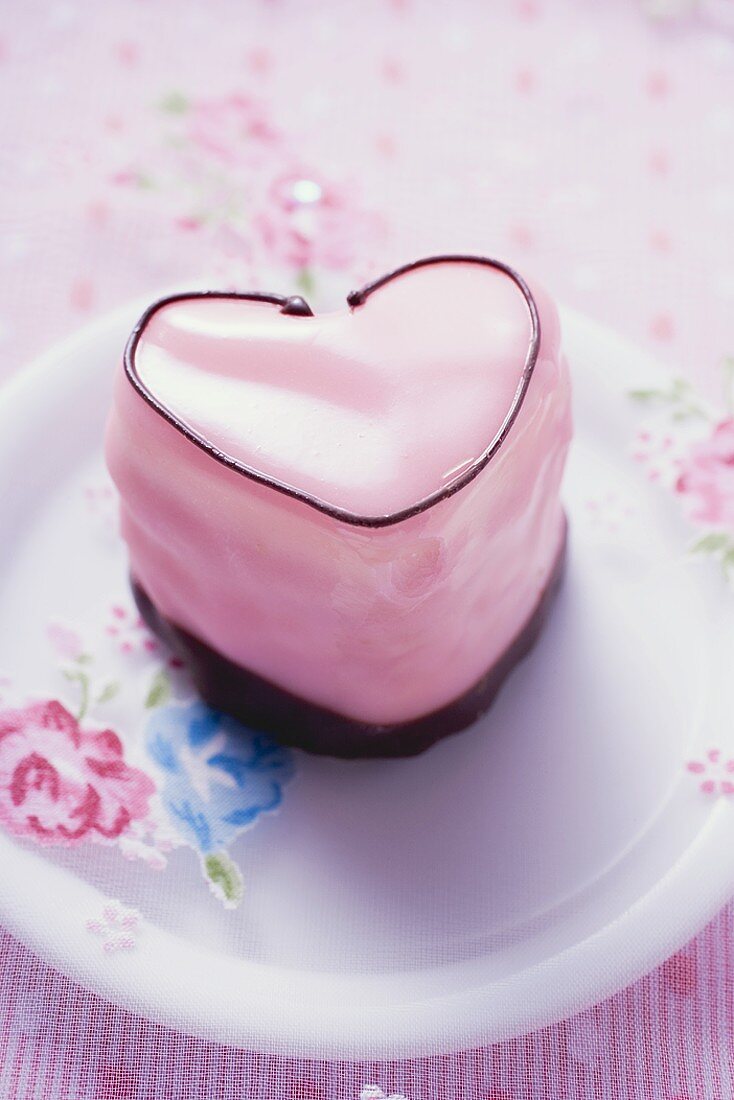 Herzförmiges rosa Petit four auf Teller