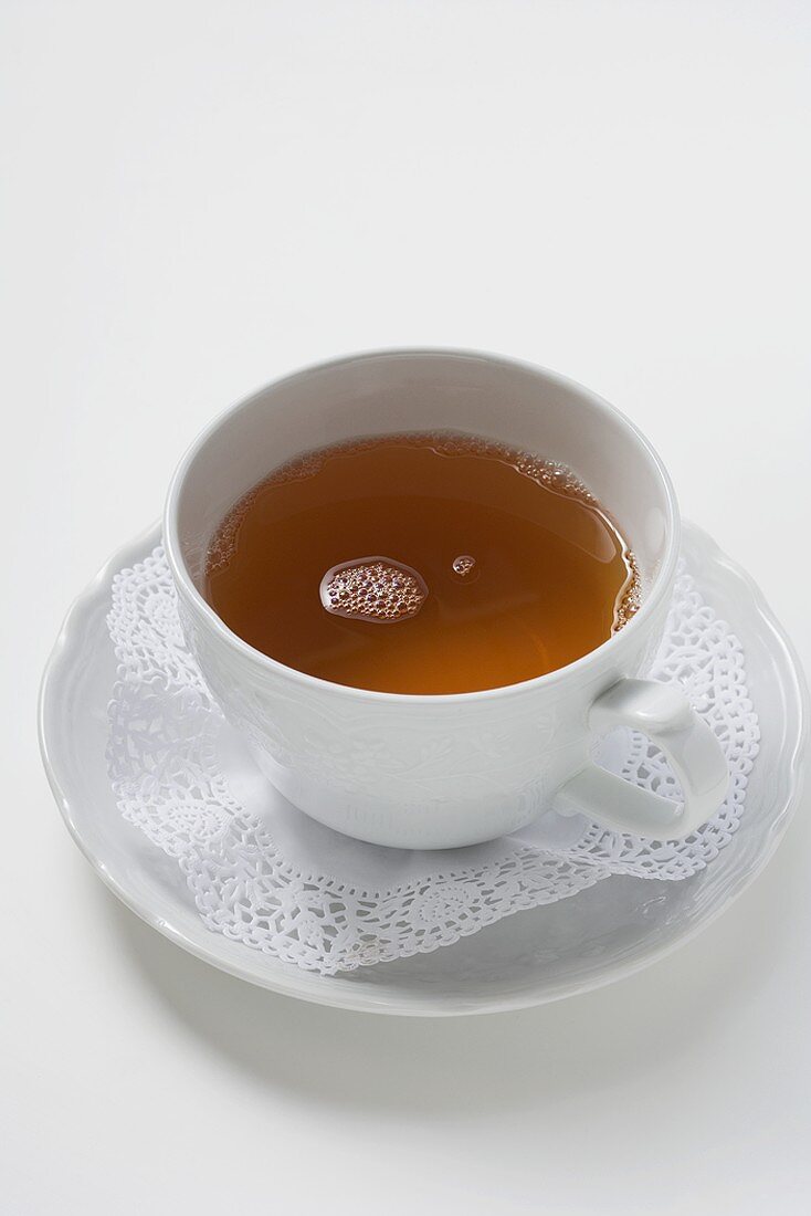 Tea in white cup and saucer with doily