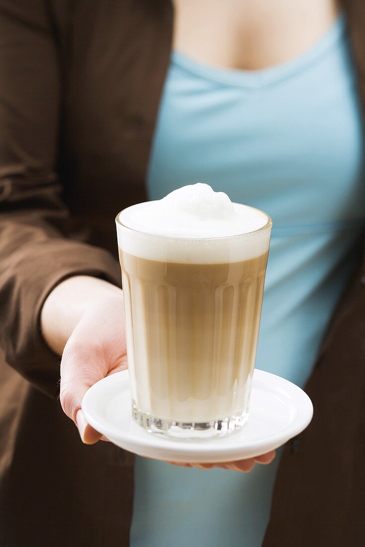 Frau hält Glas Latte Macchiato