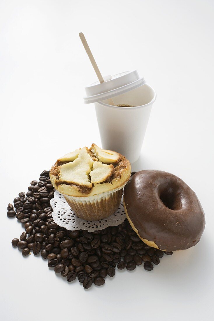 Muffin, Doughnut, Kaffeebohnen und ein Becher Kaffee