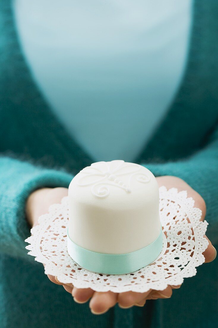 Woman holding a small white cake on a doily