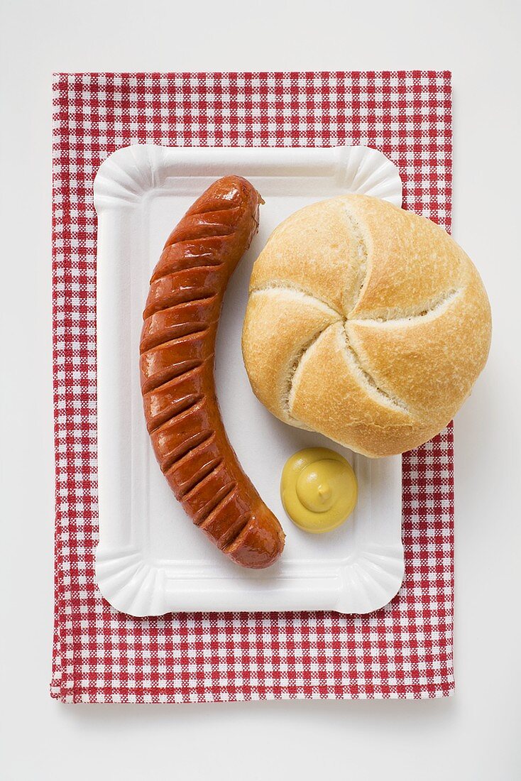 Bratwurst mit Senf und Brötchen auf Pappteller