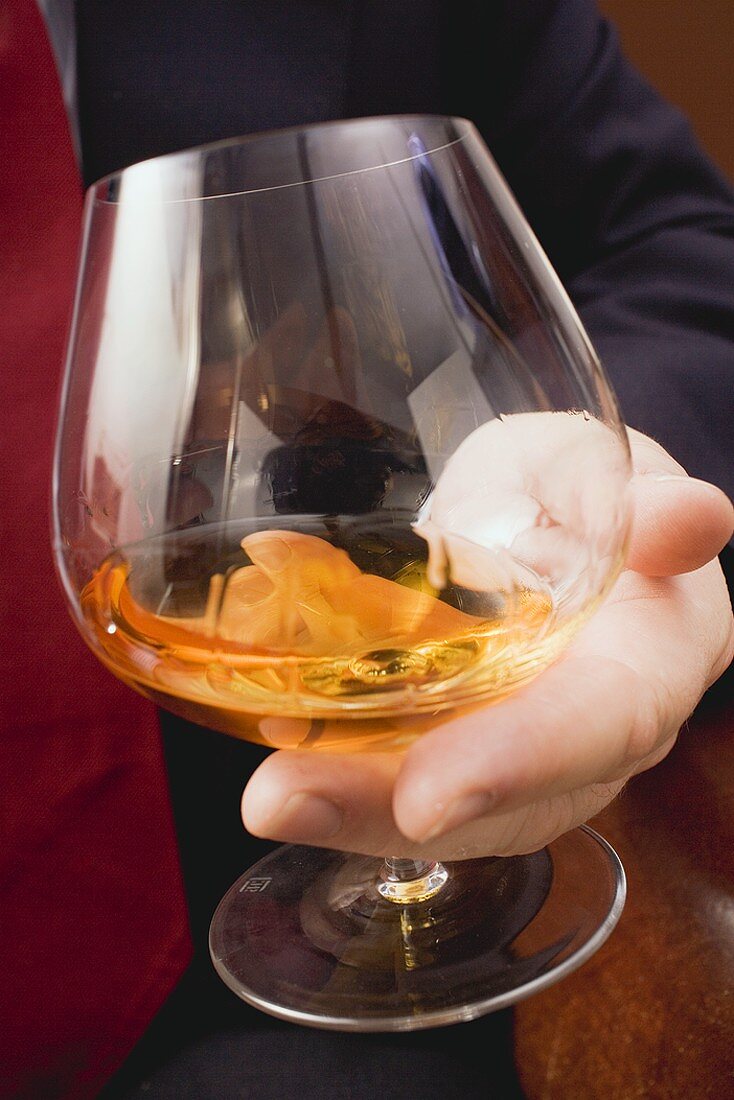 Hand holding glass of cognac