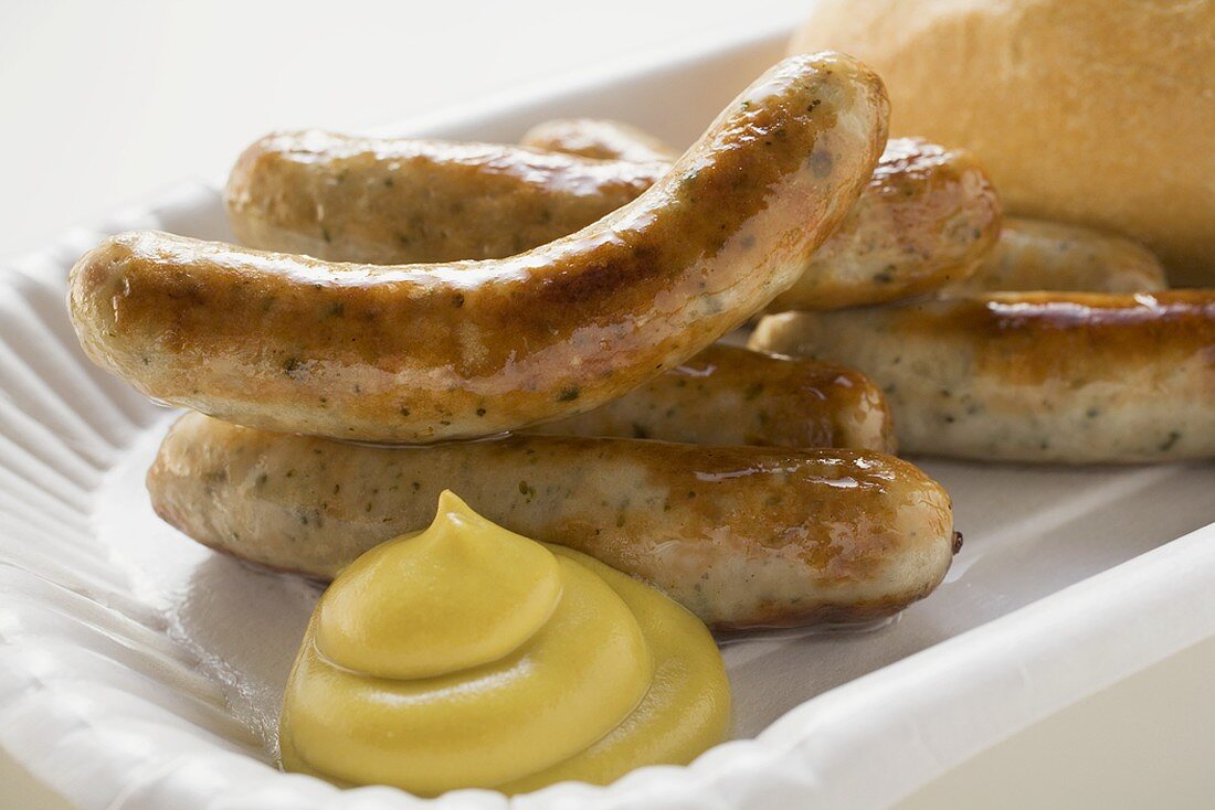 Sausages with mustard and bread roll on paper plate