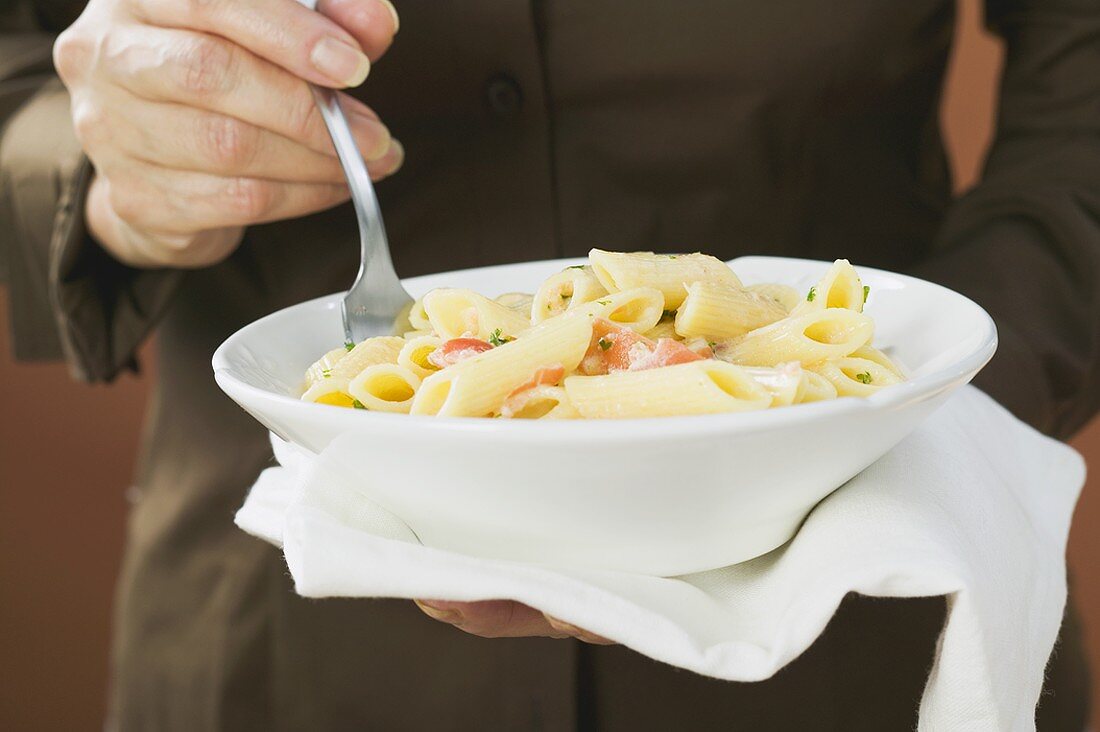 Woman eating penne with salmon and cream sauce