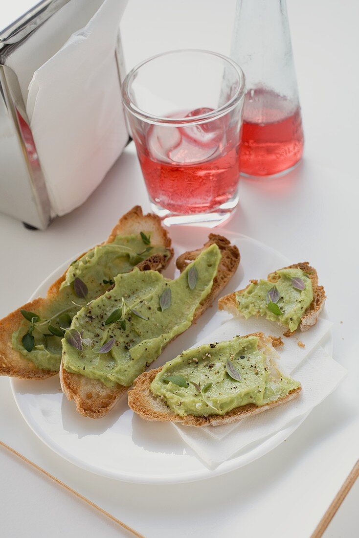 Bruschetta mit Avocadocreme auf Teller, Campari Soda