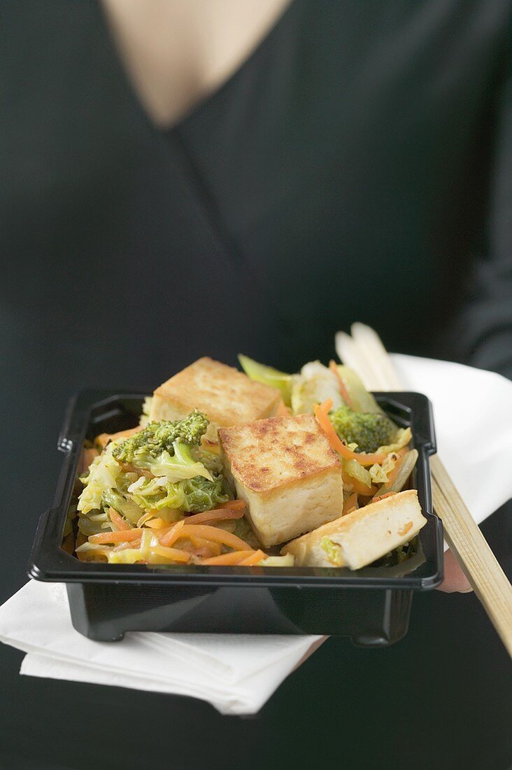 Gebratener Tofu mit Gemüse, Frau im Hintergrund (Japan)