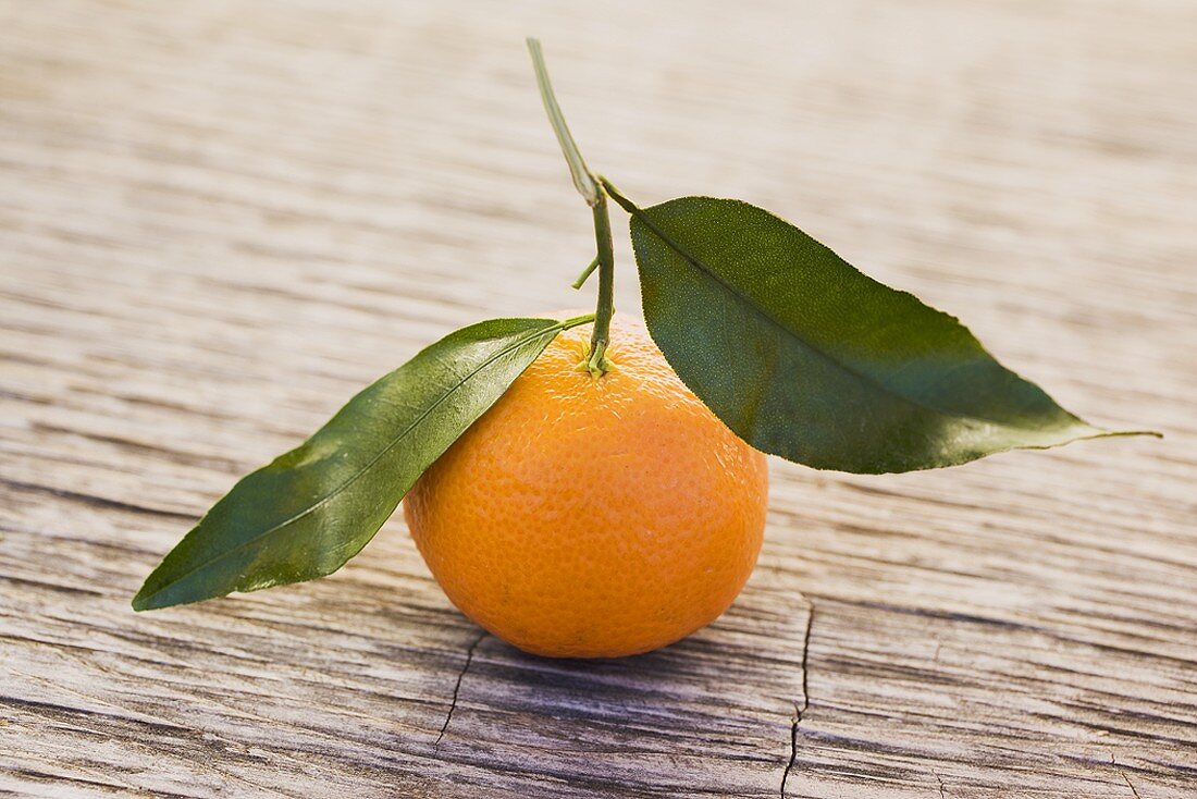 Clementine with leaves on wooden background