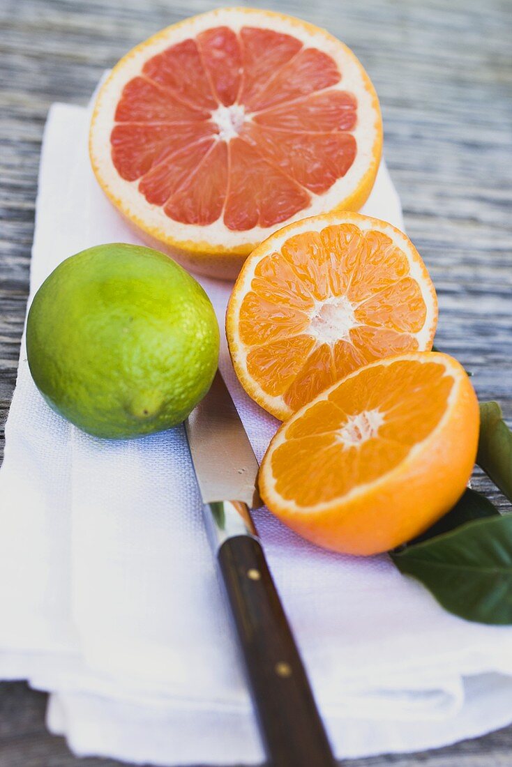 Clementine, rosa Grapefruit und Limette auf weißem Tuch