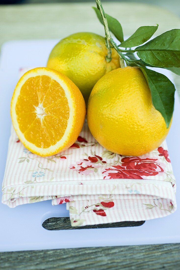 Zwei Orangen mit Blättern und halbe Clementine