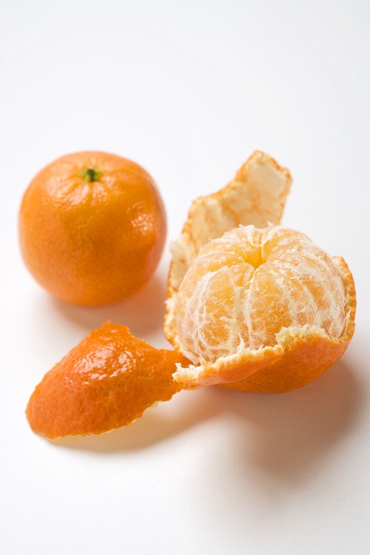 Zwei Clementinen (geschält und ungeschält)