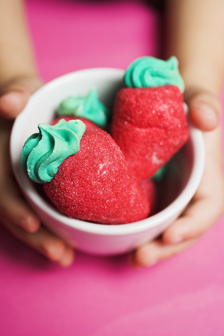 Child's hands holding small bowl of sugar strawberries