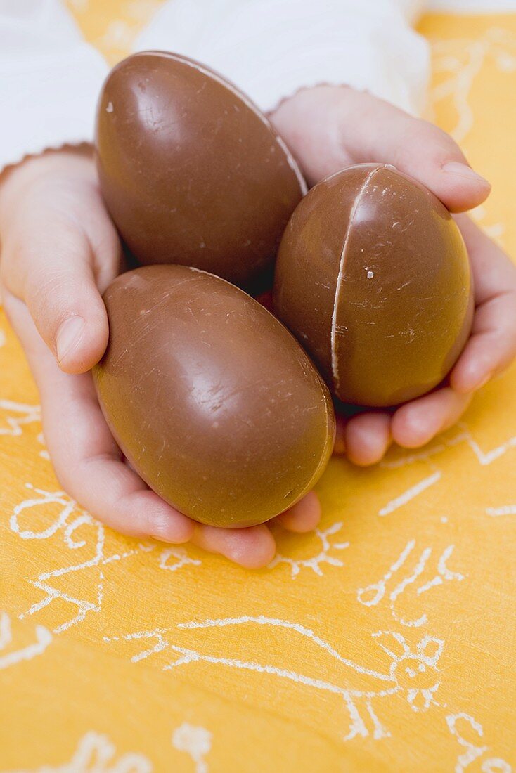 Child's hands holding three chocolate eggs