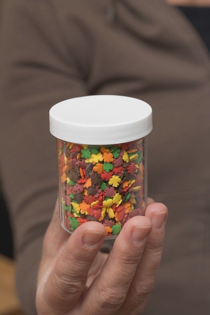 Hand holding a pot of sprinkles for Halloween