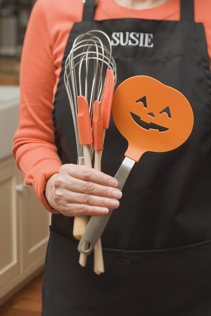 Frau hält Küchenwerkzeuge für Halloween