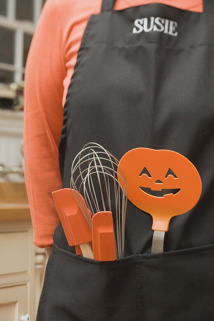 Küchenwerkzeuge für Halloween stecken in einer Schürze