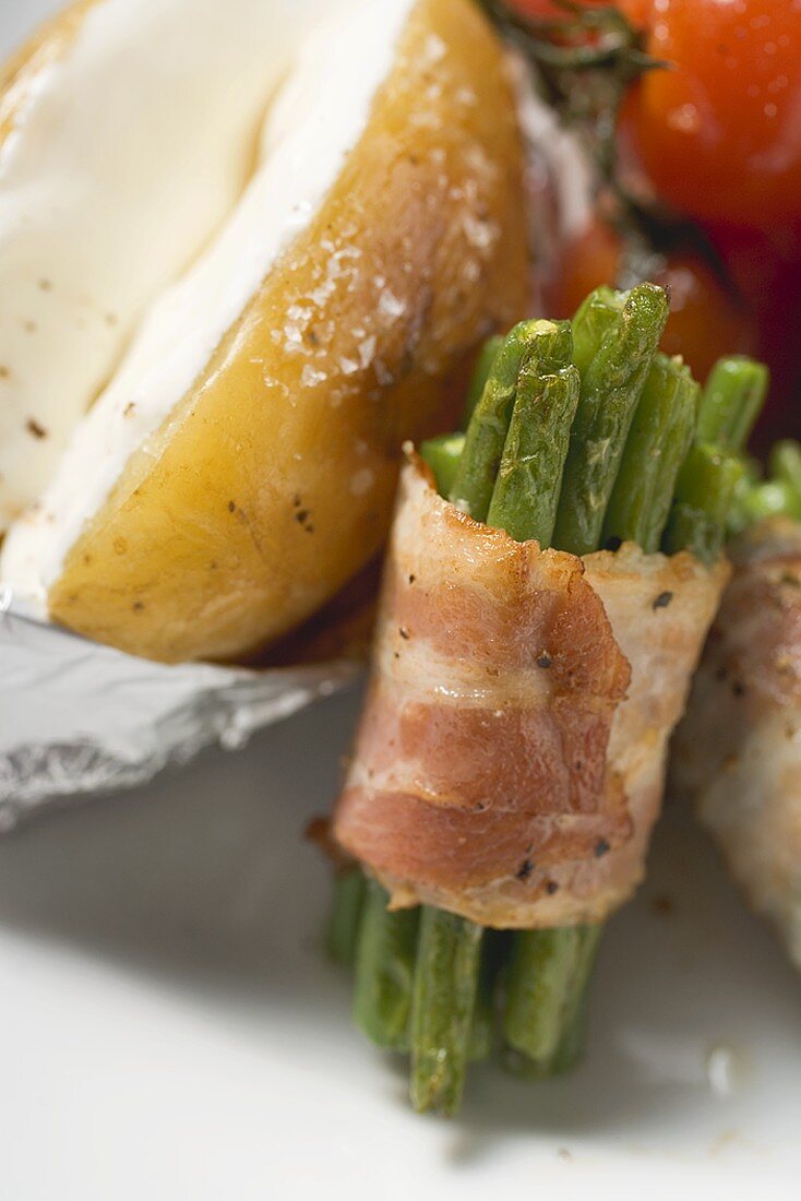 Bacon-wrapped beans, baked potato and cherry tomatoes