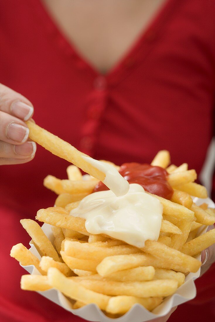 Woman dipping chip in mayonnaise
