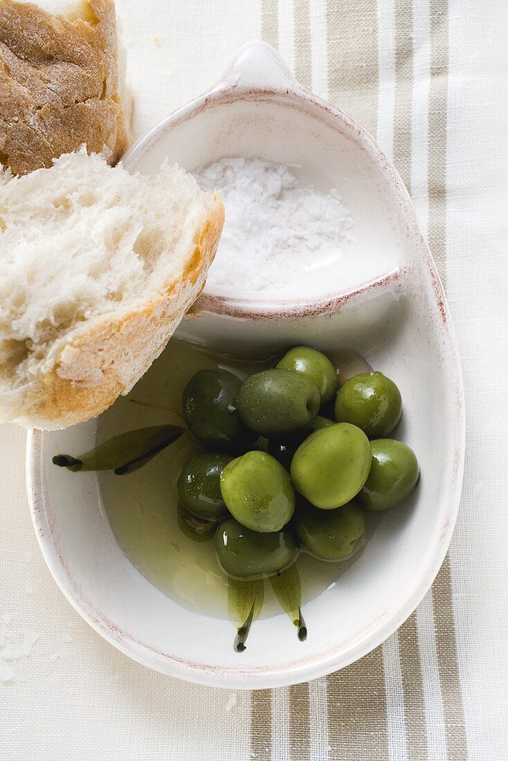 Grüne Oliven in Olivenöl mit Salz und Weißbrot