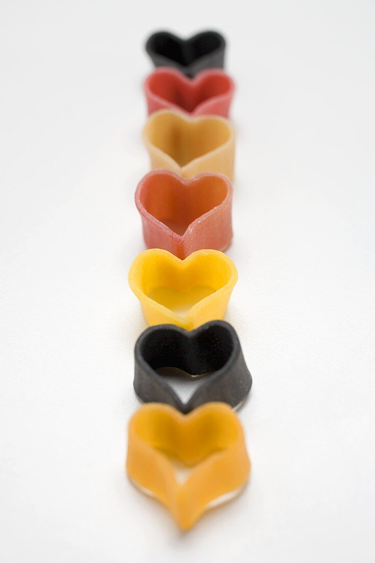 Coloured heart-shaped pasta in a row