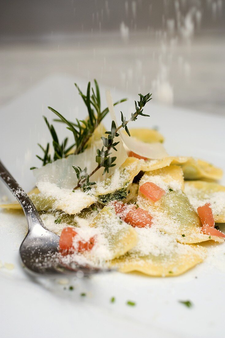 Ravioli mit Tomatenwürfeln mit Parmesan bestreuen