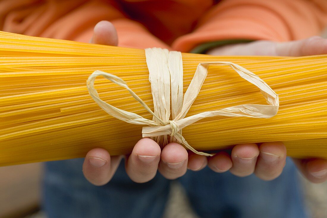 Child's hands holding a bundle of spaghetti