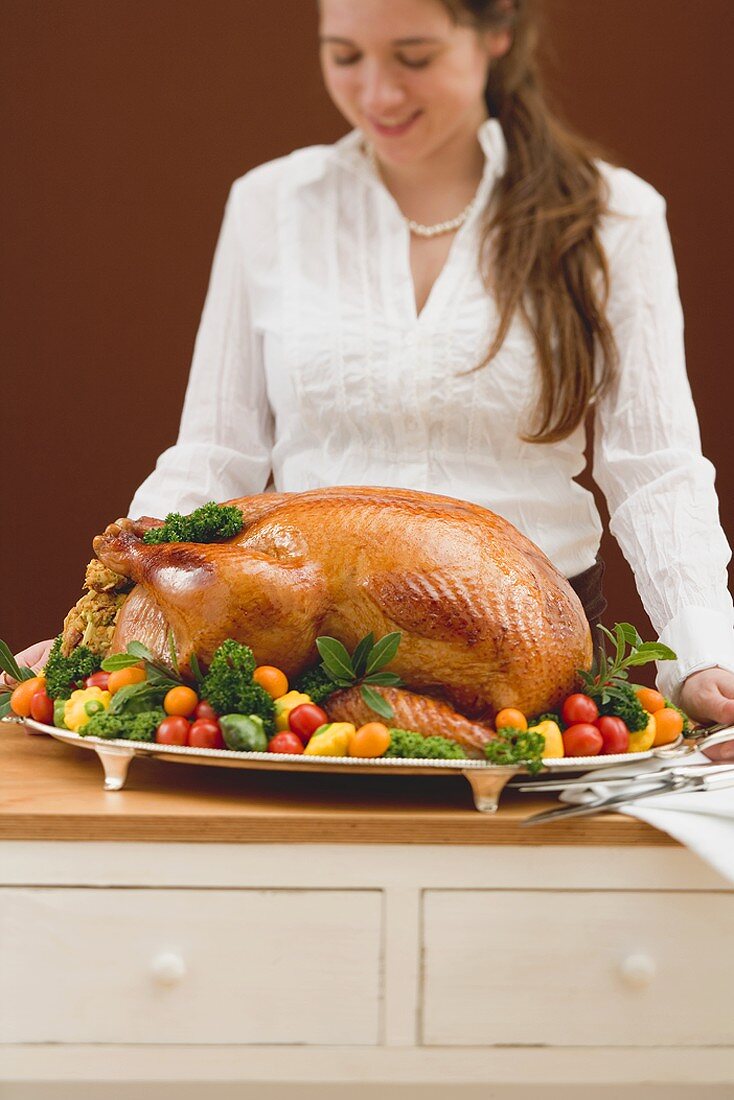 Young woman holding roast turkey on large platter