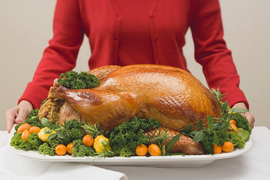 Woman holding roast turkey on large platter