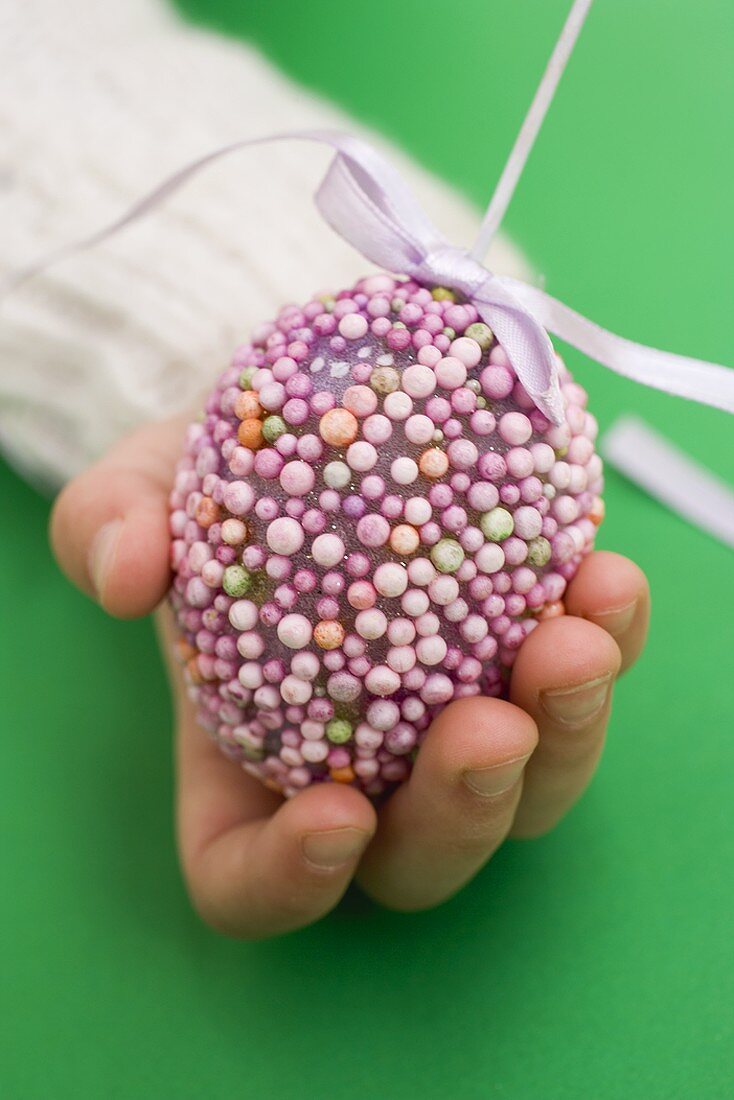 Child's hand holding purple decorated Easter egg