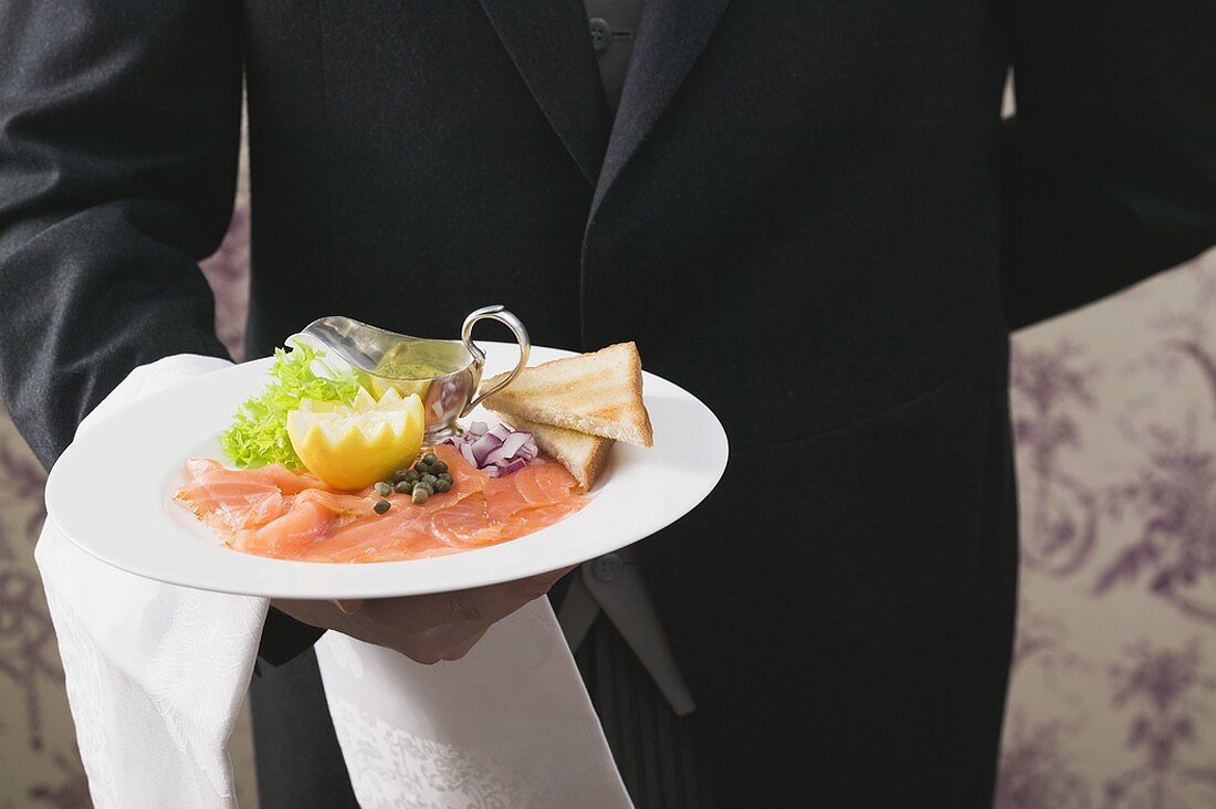 Butler serviert Räucherlachs mit Toast