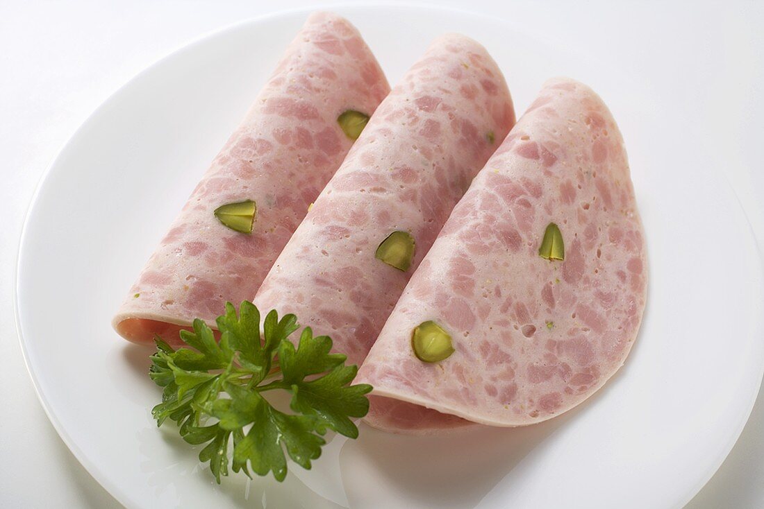 Three slices of Bierschinken (ham sausage) with parsley on plate