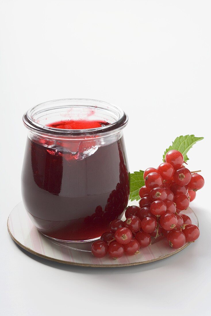 Glas Johannisbeergelee, daneben rote Johannisbeeren