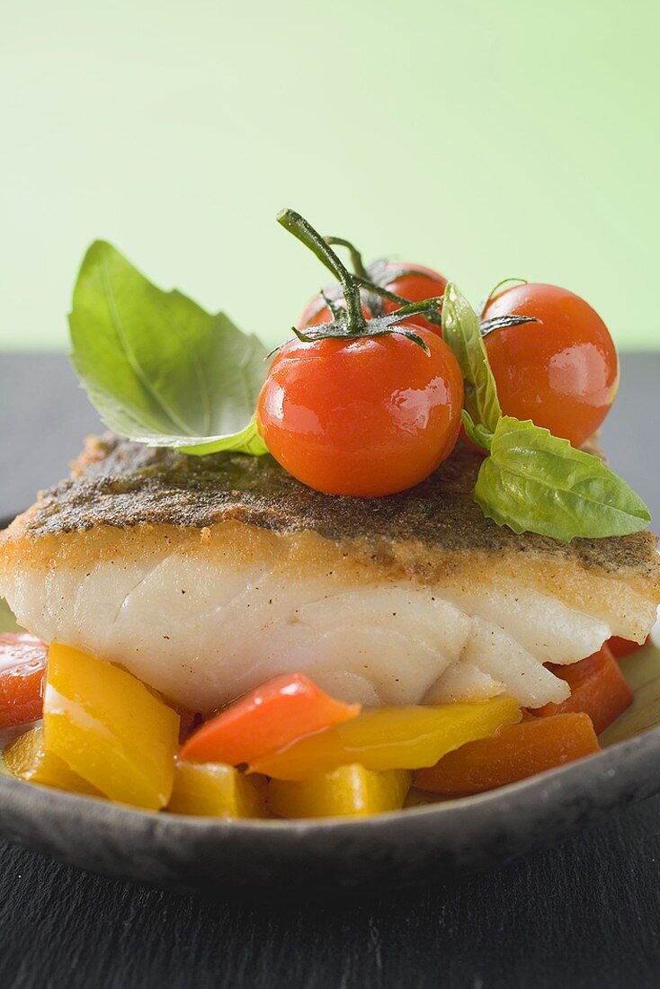 Fried fish fillet with peppers, tomatoes, basil