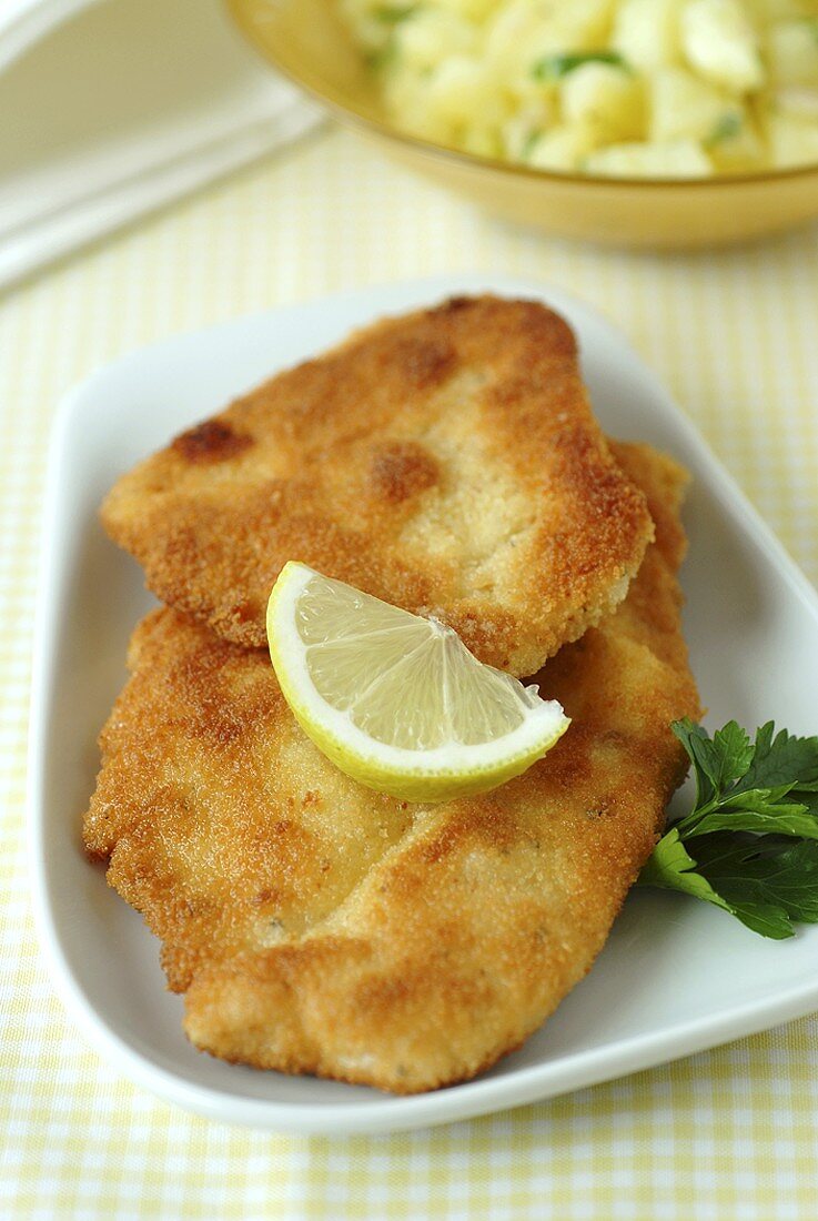 Breaded chicken escalopes, potato salad in background