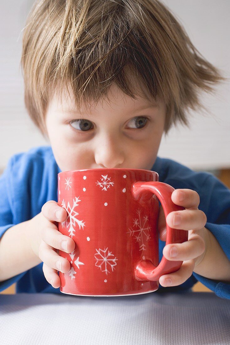 Child drinking out of large red mug