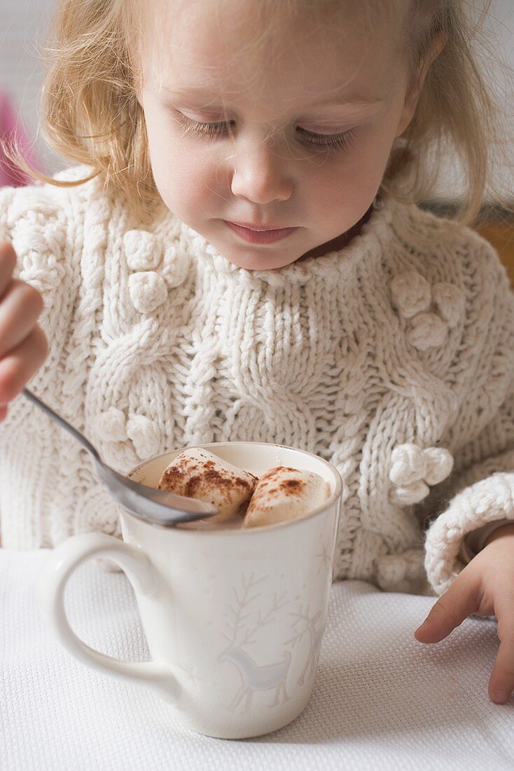 Small girl drinking cocoa with marshmallows