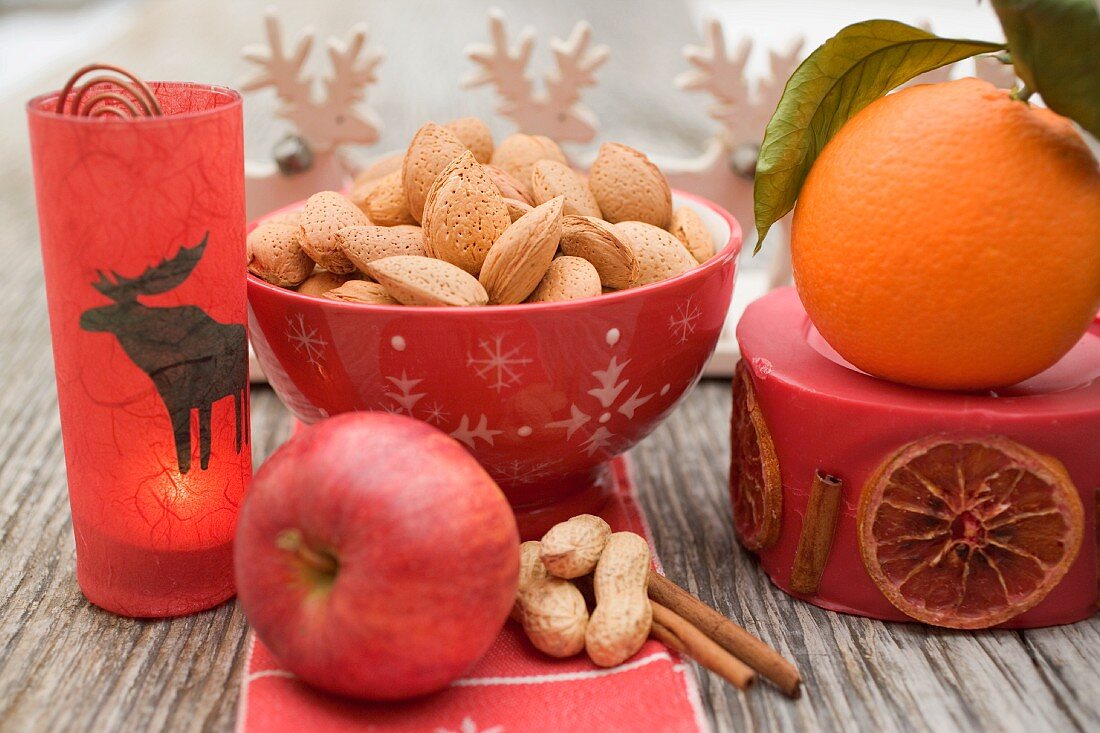 Weihnachtsdeko mit Nüssen, Orange, Apfel, Zimt und Kerze