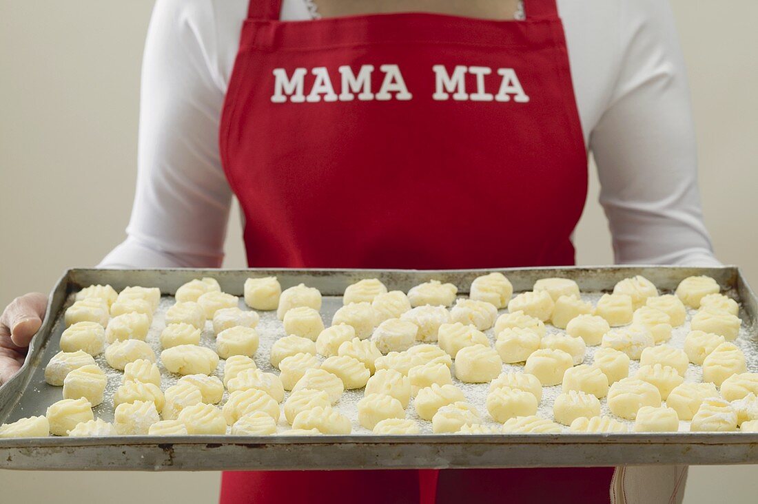 Frau hält grosses Tablett mit Gnocchi