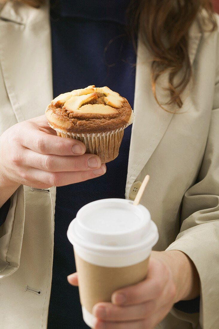 Woman holding muffin and cup of coffee