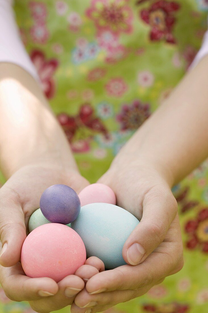 Hands holding coloured eggs