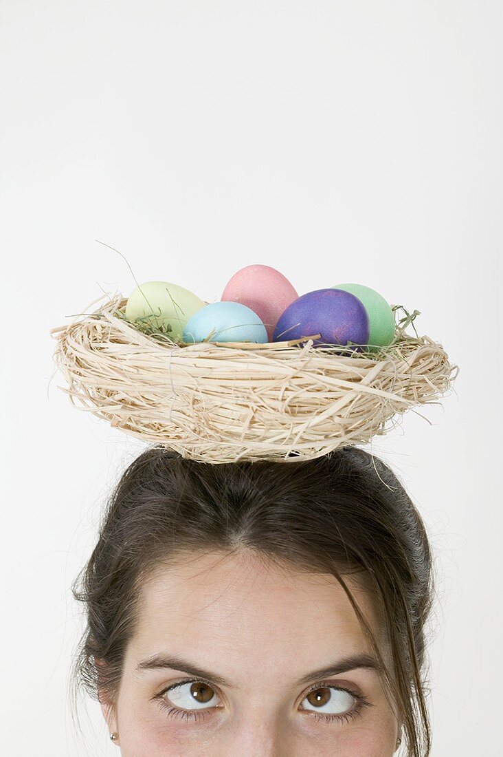 Frau trägt Korb mit gefärbten Eiern auf dem Kopf