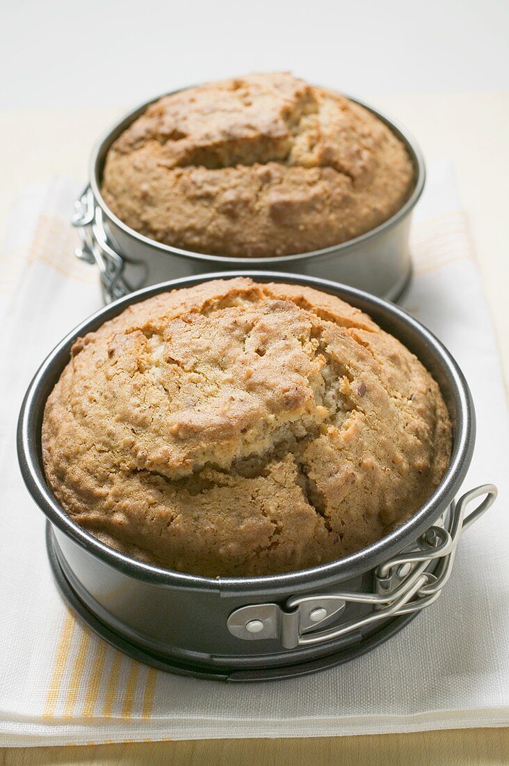 Two freshly baked cakes in baking tins