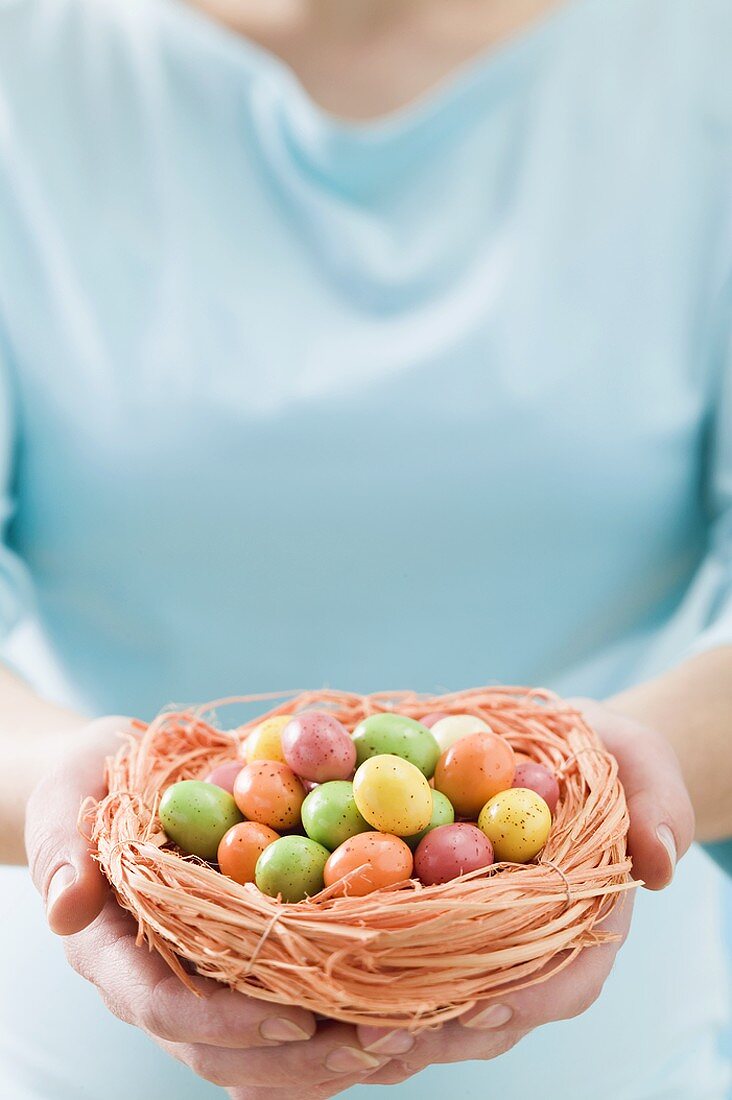 Woman holding Easter nest full of coloured sugar eggs