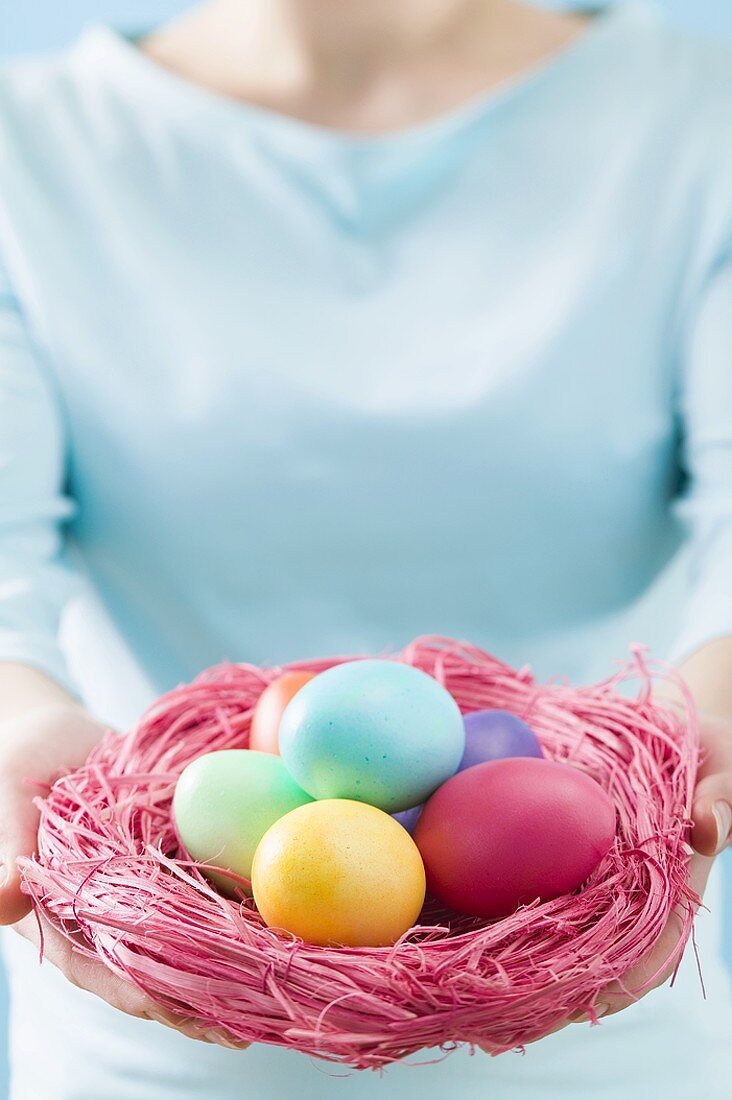 Woman holding Easter nest full of coloured Easter eggs